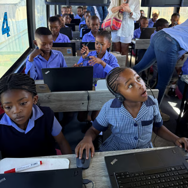 Learners in school uniform working on laptops inside the DigiBus