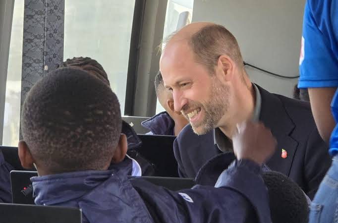 A learner showing his work on a laptop to a visitor inside the DigiBus during the 2024 royal visit