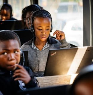 Learners working on laptops with headsets inside the DigiBus
