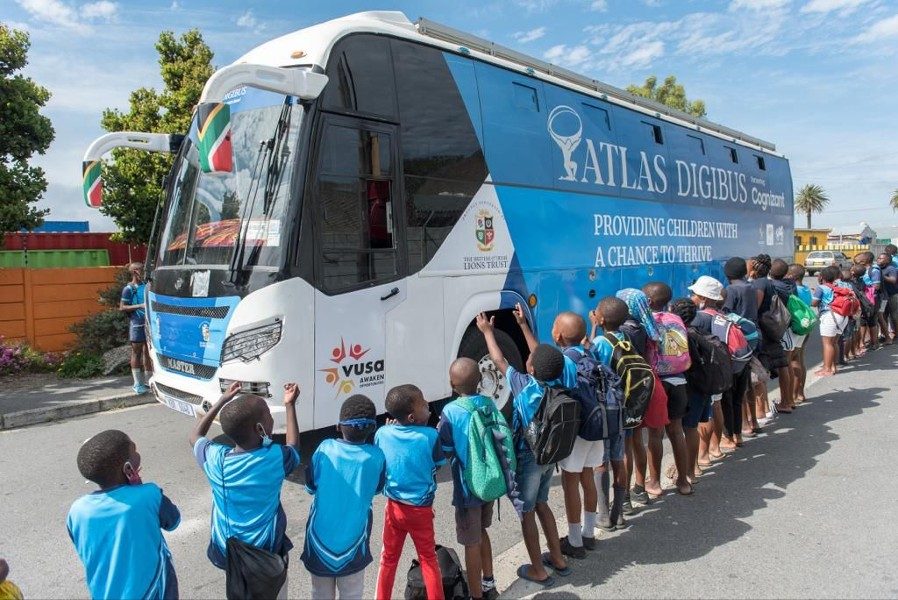 A queue of primary school children waiting to board the Atlas DigiBus outside their school